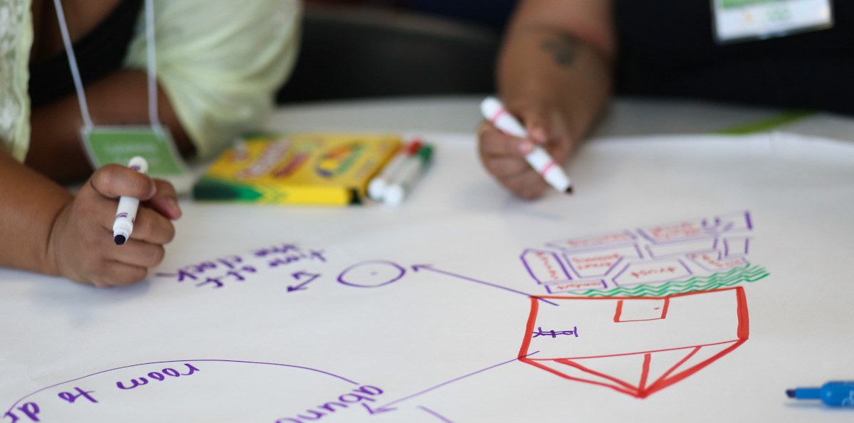 Photo of two people drawing plans on large paper with colored pens