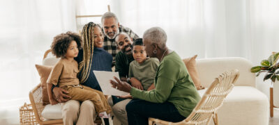 Multi-generational family sits together on a cream-colored sofa. Photo: iStock/Getty Images