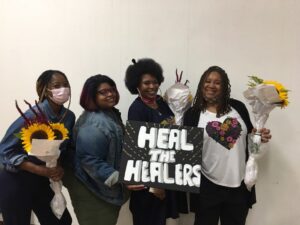 Abundance of Hope members hold a sign that says "heal the healers