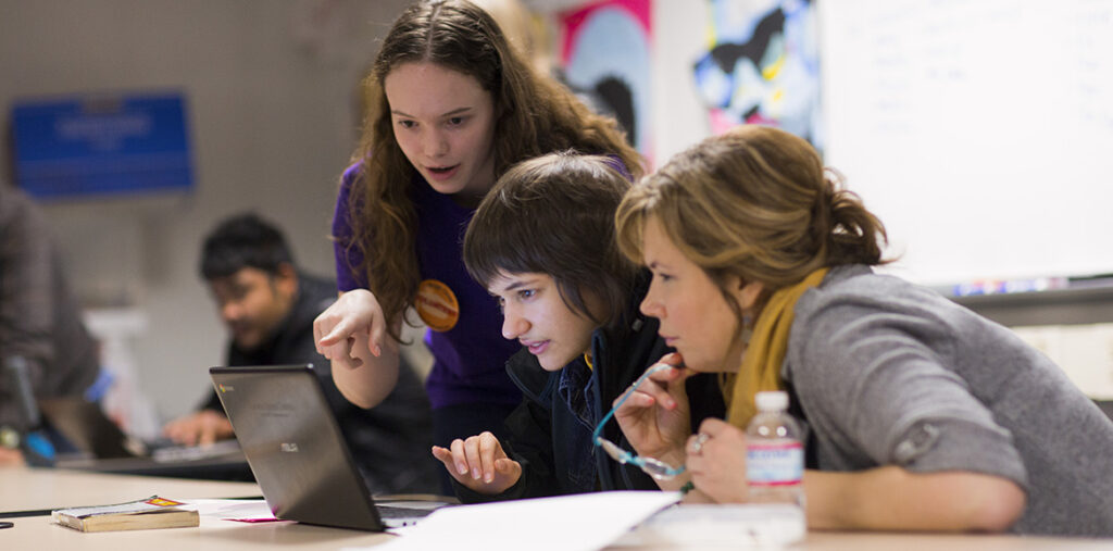 students gathered around looking at computer