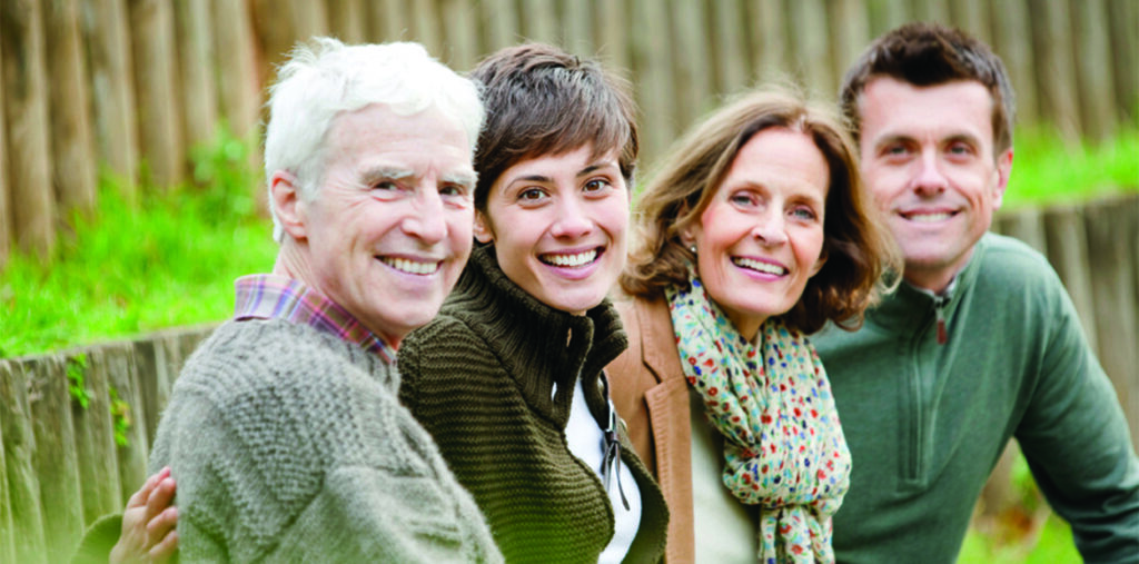 Family sitting outside on a bench smiling